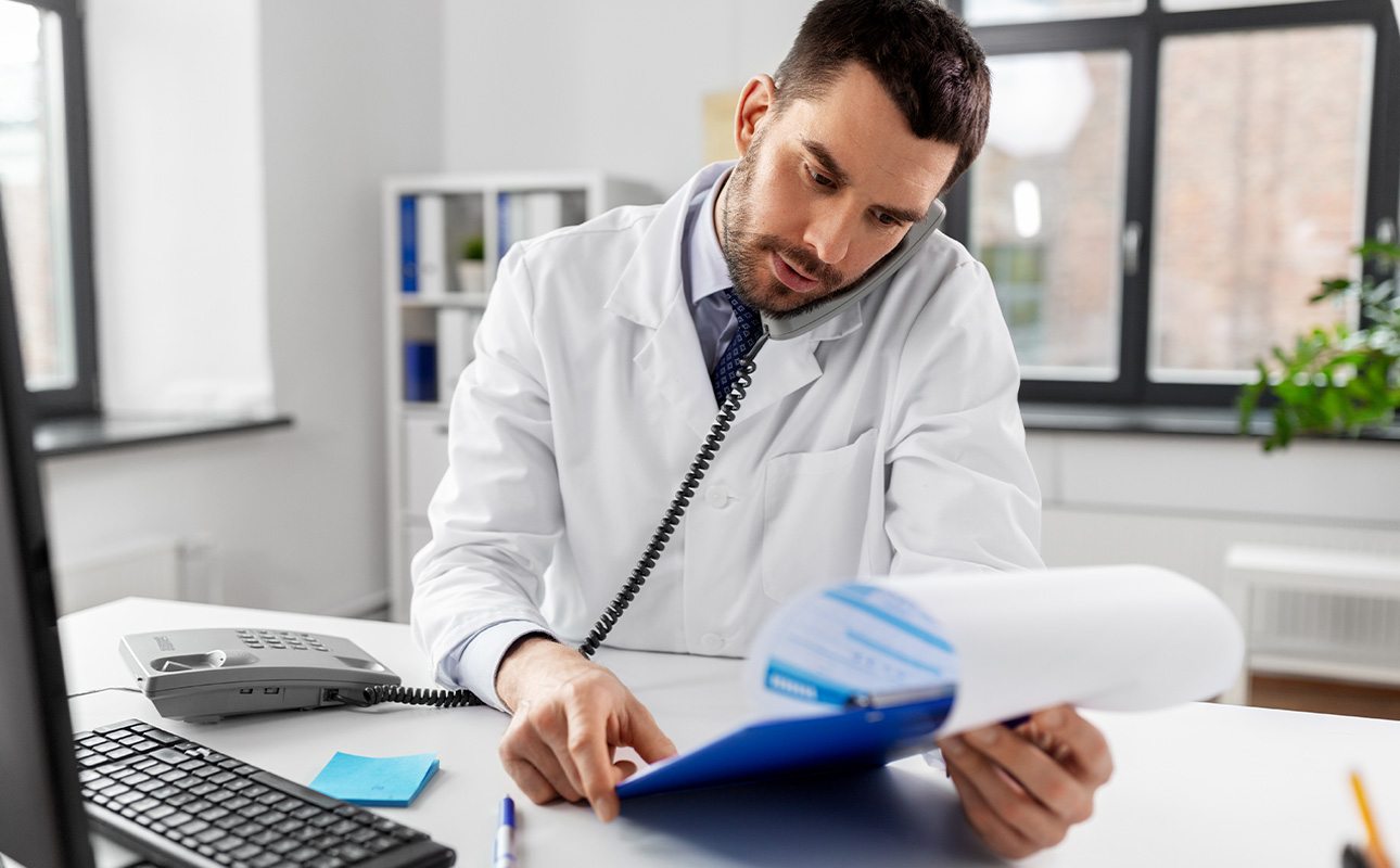 Médico revisando planilhas contábeis com atenção aos impostos.
